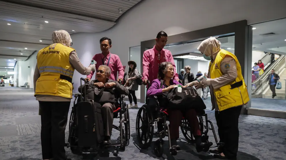 Personal de un aeropuerto internacional de Indonesia mide la temperatura a los pasajeros que llegan que llegan