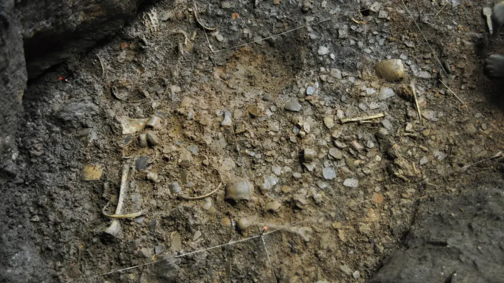 Imagen de distintos restos humanos entre el pavimento de cerámicas de la primera ocupación de la cueva.