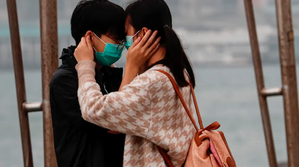 Una pareja con mascarilla se abraza en Hong Kong.