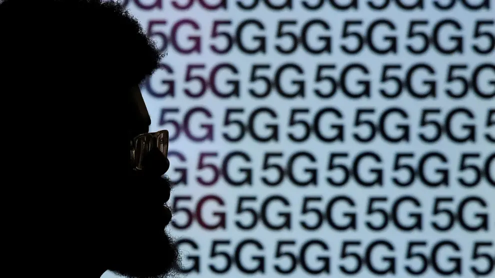 FILE PHOTO: A man walks past an advertisement promoting the 5G data network at a mobile phone store in London, Britain, January 28, 2020. REUTERS/Toby Melville/File Photo [[[REUTERS VOCENTO]]] BRITAIN-5G/THREE
