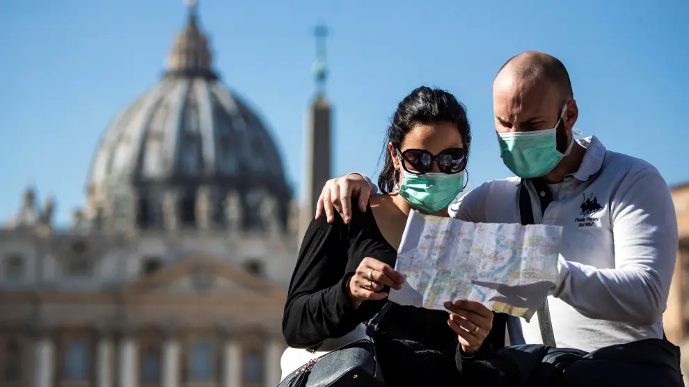 Una pareja de turistas con máscaras faciales visita la plaza de San Pedro en el Vaticano.