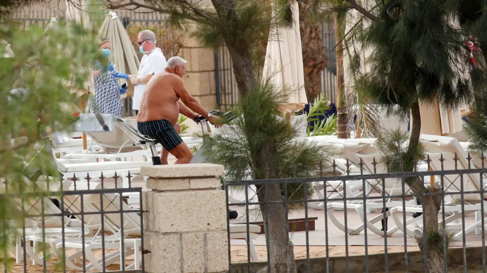 Tourists wearing face masks are seen next to the pool of H10 Costa Adeje Palace, which is on lockdown after cases of coronavirus have been detected there in Adeje