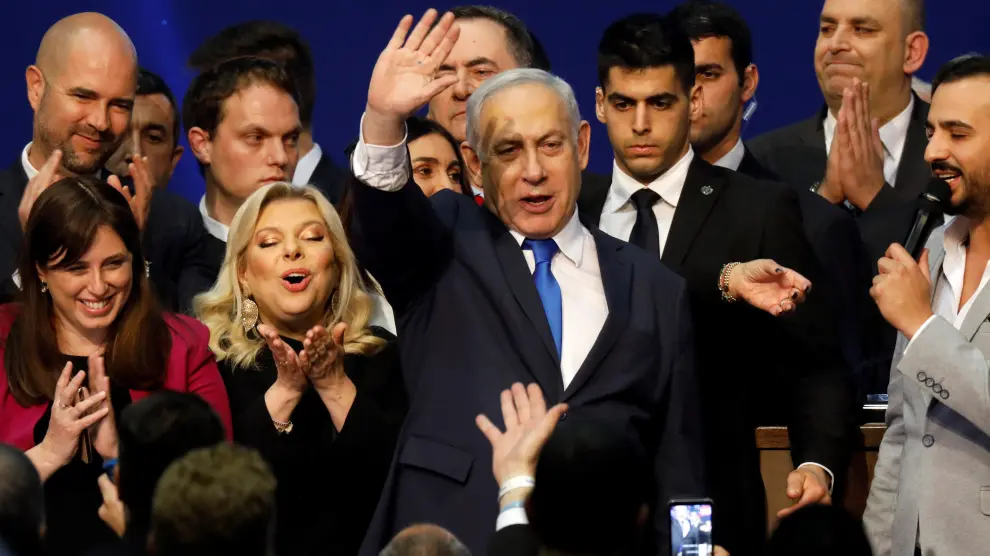 Israeli Prime Minister Benjamin Netanyahu stands next to his wife Sara as he waves to supporters following the announcement of exit polls in Israel's election at his Likud party headquarters in Tel Aviv