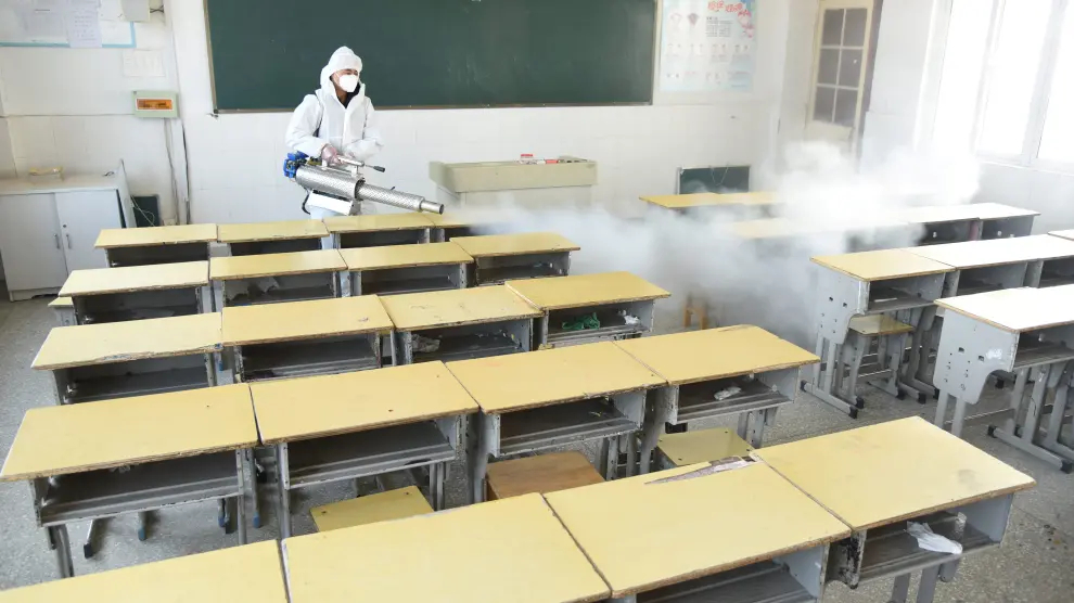 Worker in protective suit sprays disinfectant inside a classroom of a primary school, as students’ return has been delayed due to the novel coronavirus outbreak, in Donghai county of Lianyungang, Jiangsu