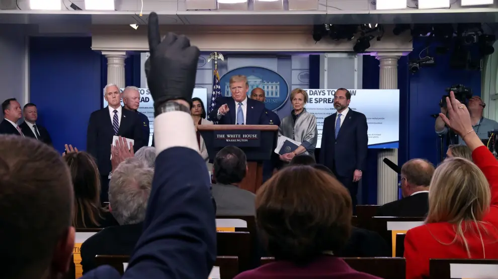 A reporter wears a latex glove while trying to ask a question of U.S. President Donald Trump during a news briefing on the coronavirus (COVID-19) at the White House in Washington