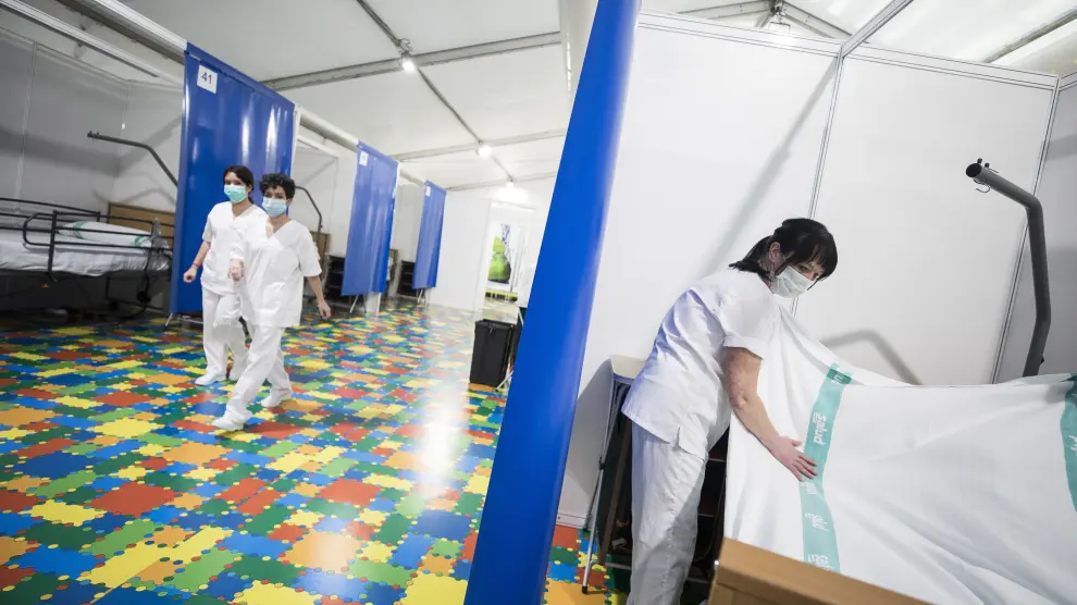 Una trabajadora prepara una de las 35 primeras camas del hospital de campaña de la Multiusos