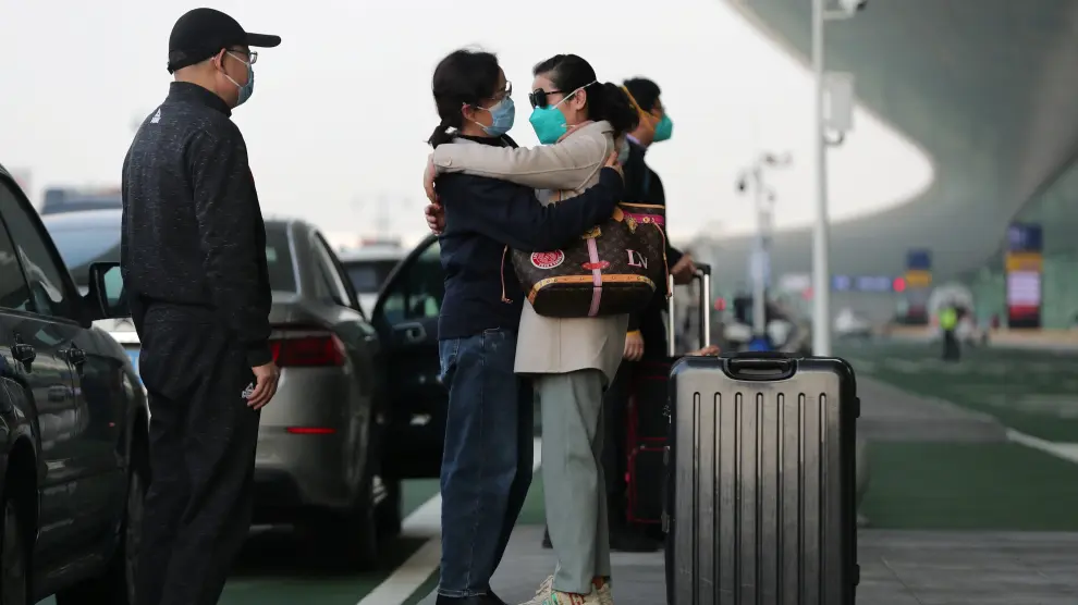 Traveller wearing a face mask hugs a woman outside Wuhan Tianhe International Airport in Wuhan