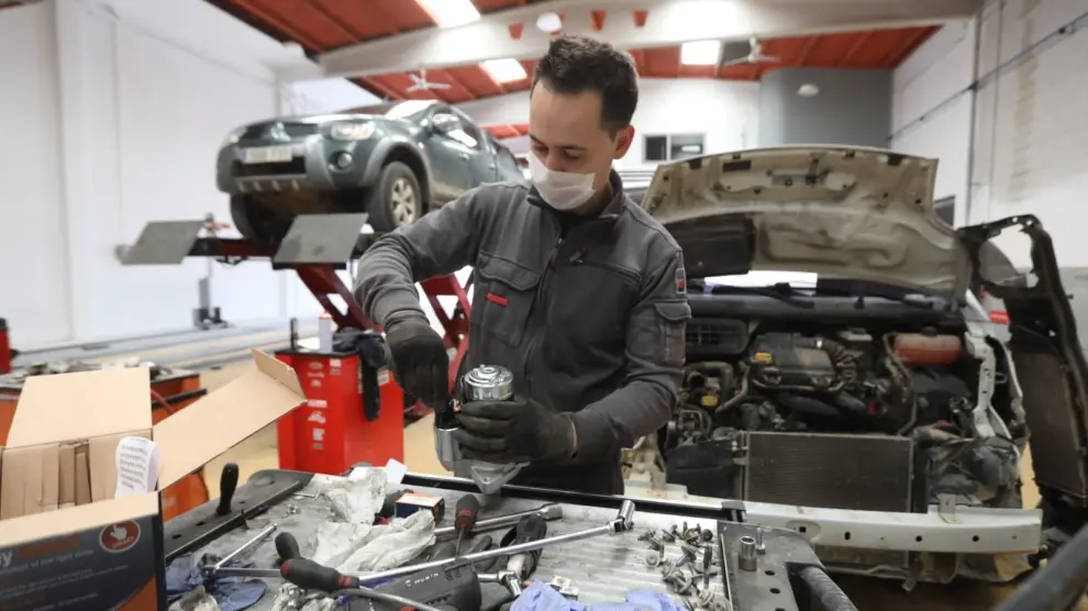 Un trabajador con mascarilla en un taller de reparación de automóviles en Huesca.