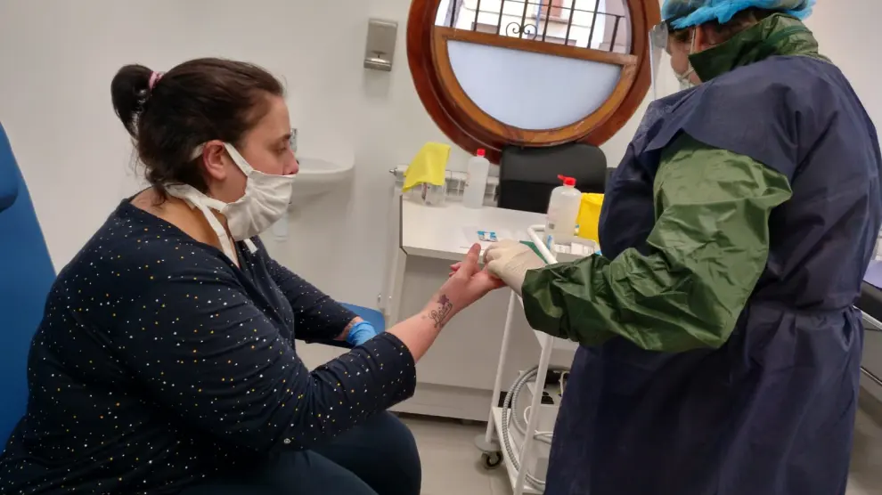 Una enfermera realiza un test rápido de coronavirus a una vecina en Utrillas
