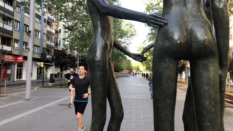 Corredores pasan por la escultura Complicidad de Alberto Gómez Ascaso