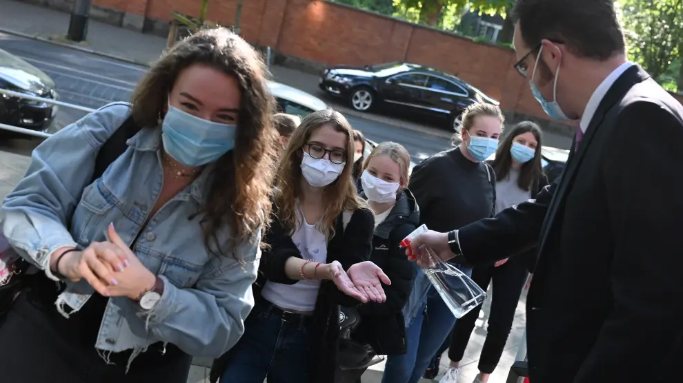 27 April 2020, Hessen, Frankfurt: A teacher sprays hand disinfectant on the hands of the students before entering the school as particular pupils are back in school after a six-week break. Photo: Arne Dedert/dpa27/04/2020 ONLY FOR USE IN SPAIN [[[EP]]] 27 April 2020, Hessen, Frankfurt: A teacher sprays hand disinfectant on the hands of the students before entering the school as particular pupils are back in school after a six-week break. Photo: Arne Dedert/dpa