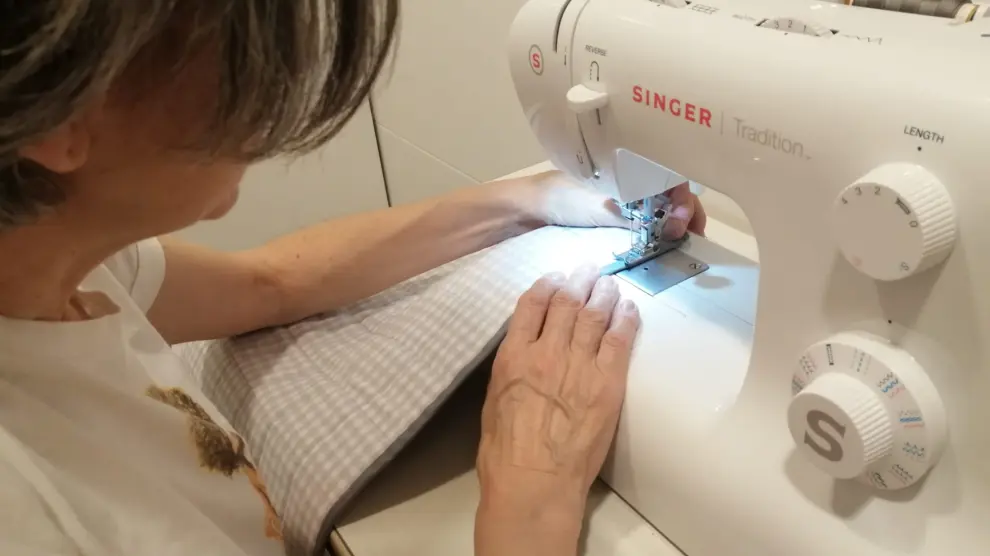 Una mujer trabaja con su máquina de coser en su domicilio de Zaragoza.