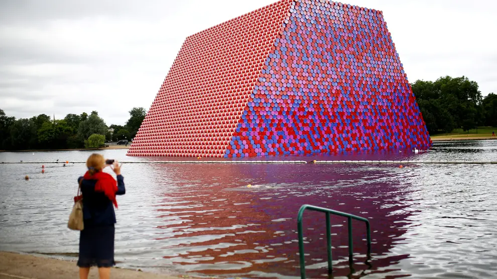 FILE PHOTO: A woman photographs swimmers exercising in the Serpentine River in front of Christo's "The London Mastaba", in Hyde Park, London