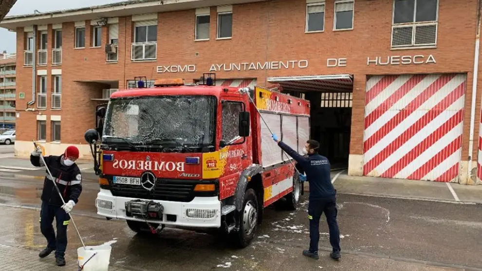 Bomberos de Huesca limpiando uno de los camiones a las puertas del parque.