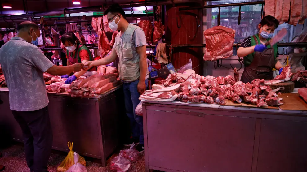 customer wearing a face mask pays for pork as a vendor chops pork meat inside the Yuegezhuang wholesale market, following new cases of coronavirus disease (COVID-19) infections in Beijing