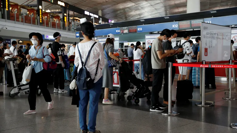 People wearing protective gear line up at Beijing Capital International Airport