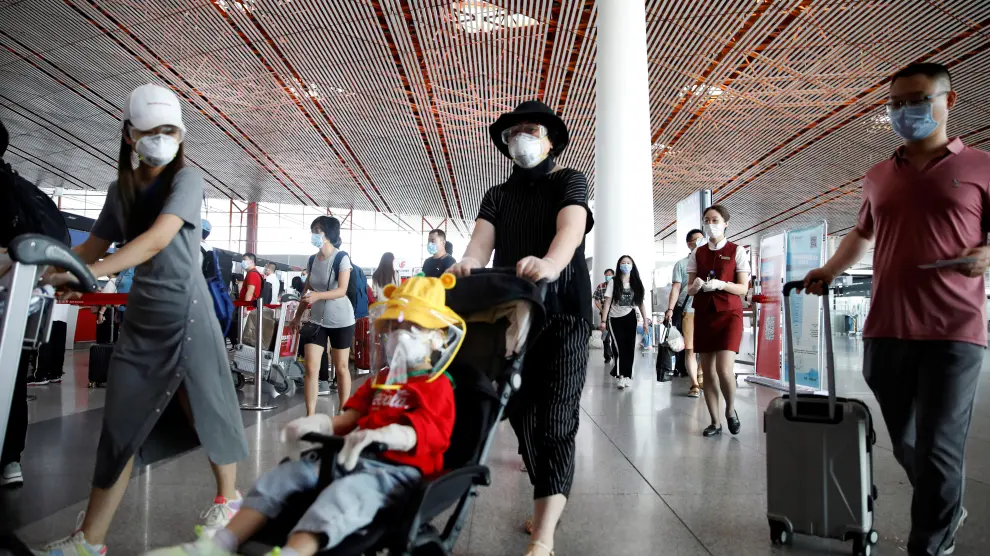 Travellers wearing protective gear are seen at the departure hall of Beijing Capital International Airport