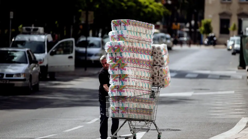 Un trabajador de un supermercado con rollos de papel higiénico.