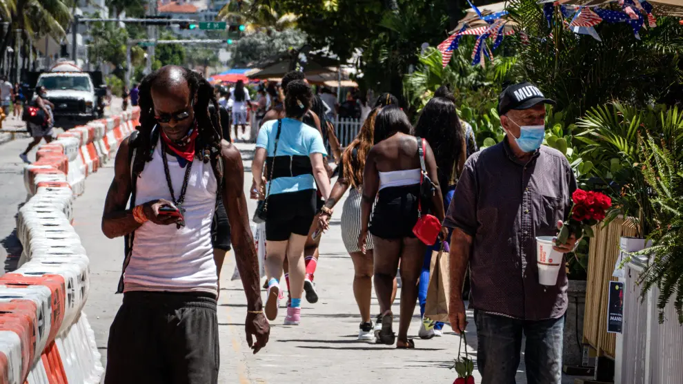 Personas con y sin mascarilla pasean por Miami Beach (Florida).