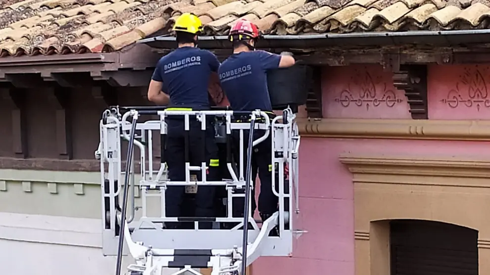 Los bomberos retiran material desprendido en el alero de un edificio del Coso Bajo