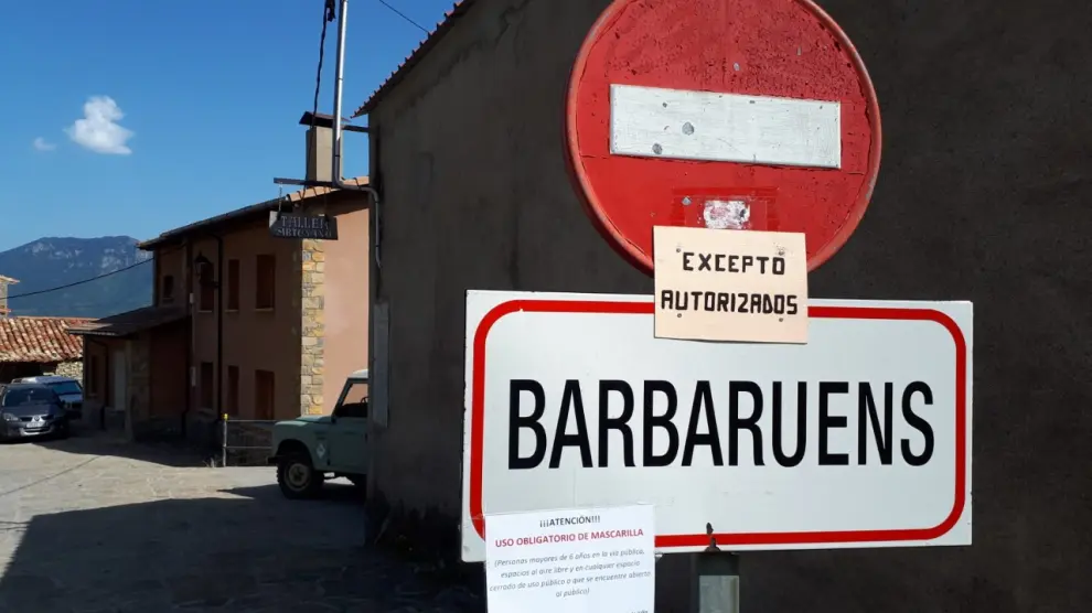 Un cartel a la entrada del pueblo de Barbaruens recuerda la obligación de llevar mascarilla, aunque sea en espacios al aire libre.
