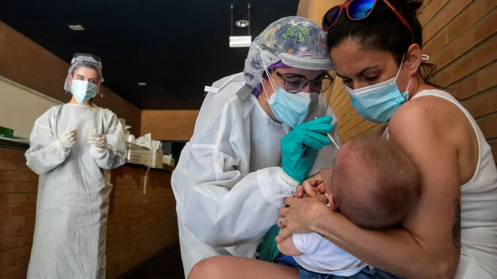 Una sanitaria realiza un test PCR a un niño en un espacio habilitado en un centro de salud de Zaragoza.