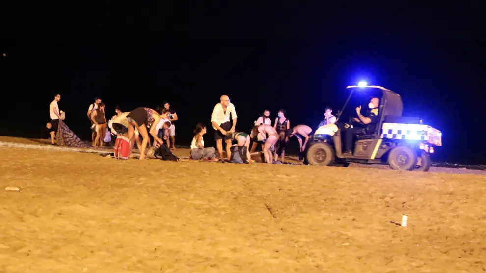 Un policía llama la atención a un grupo de personas en la playa de la Barceloneta, el sábado en Barcelona.
