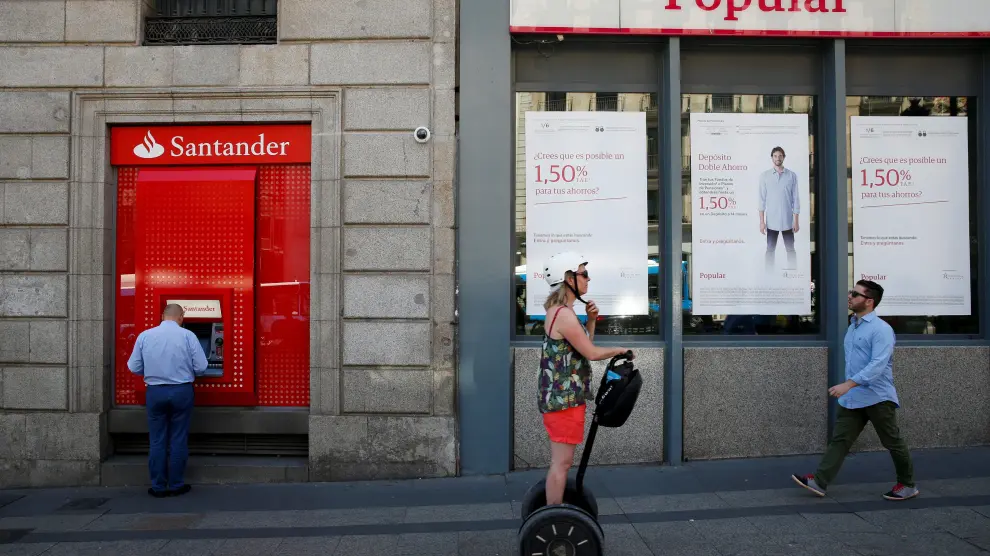 A man uses a cash dispenser at a branch of Spain's biggest bank Santander next to a Banco Popular branch on the same day Santander announced that it would buy struggling rival Banco Popular for a nominal one euro after European authorities determined the lender was on the verge of insolvency, in Madrid, Spain June 7, 2017. REUTERS/Juan Medina TPX IMAGES OF THE DAY [[[REUTERS VOCENTO]]] [[[HA ARCHIVO]]] POPULAR-M-A/SANTANDER