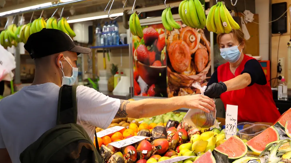 Un turista compra fruta en el mercado de Valencia.
