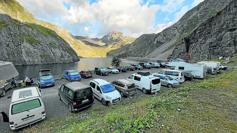 Vehículos aparcados de la presa de Llauset (Montanuy), de camino al refugio, con muchas furgonetas y autocaravanas, habituales este año