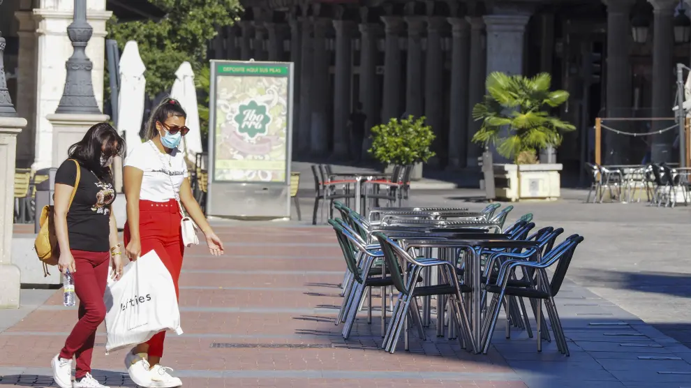 Dos mujeres caminan junto a una terraza vacía de un bar en la plaza Mayor de Valladolid, este miércoles