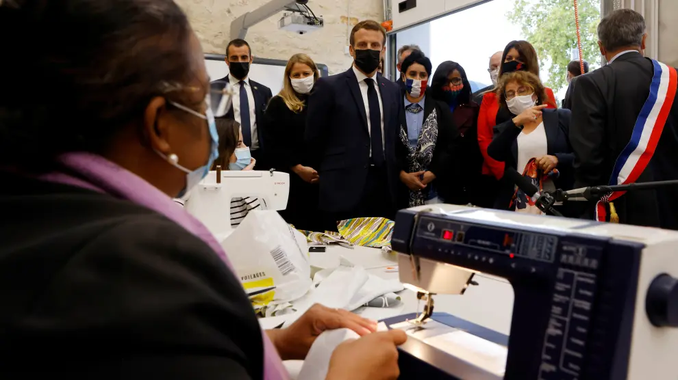 French President Emmanuel Macron talks with people sewing face masks during his visit to the Ateliers du Moulin, in Les Mureaux, near Paris