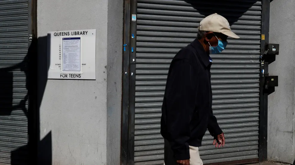 A man walks with a protective face mask past a closed library amid the coronavirus disease (COVID-19) outbreak in the Far Rockaway section of the Queens borough of New York
