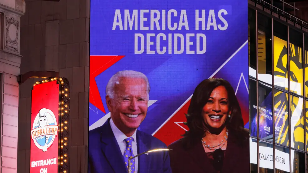 People celebrate as media announced that Democratic U.S. presidential nominee Joe Biden and vice presidential nominee Kamala Harris (seen on screen) have won the 2020 U.S. presidential election on Times Square in New York City