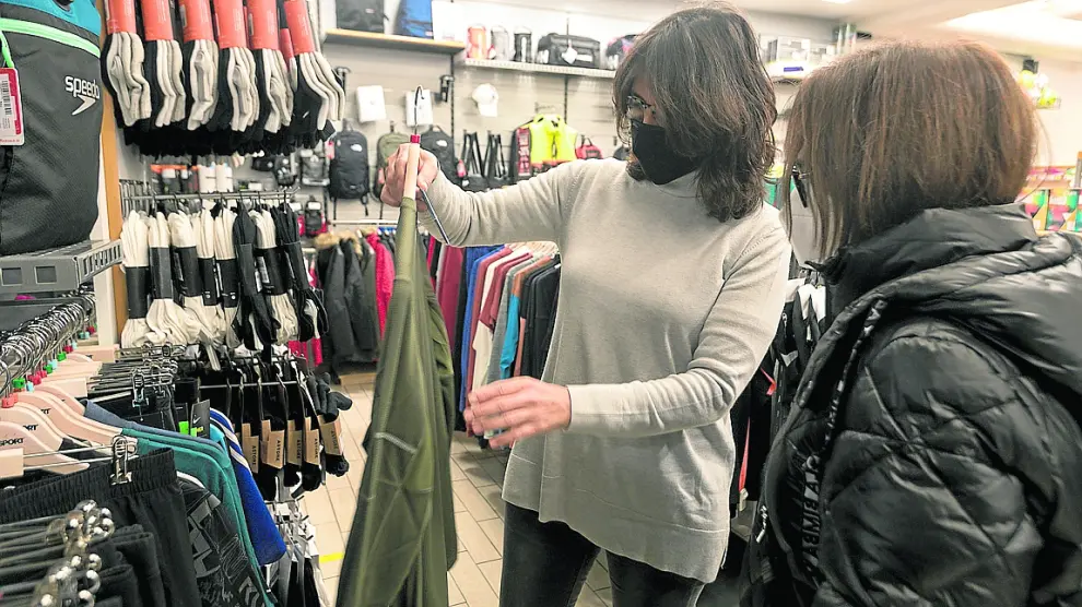 Gemma Cajal, de Intersport Huesca, enseña una prenda a una cliente en su tienda.