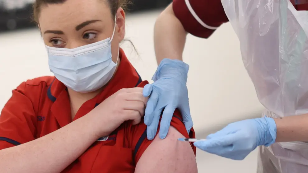 A woman receives the first of two Pfizer/BioNTech COVID-19 vaccine jabs at a vaccination centre, on the first day of the largest immunisation programme in the British history, in Cardiff, Wales, Britain December 8, 2020. Ben Birchall/Pool via REUTERS[[[REUTERS VOCENTO]]] HEALTH-CORONAVIRUS/BRITAIN-ROLLOUT