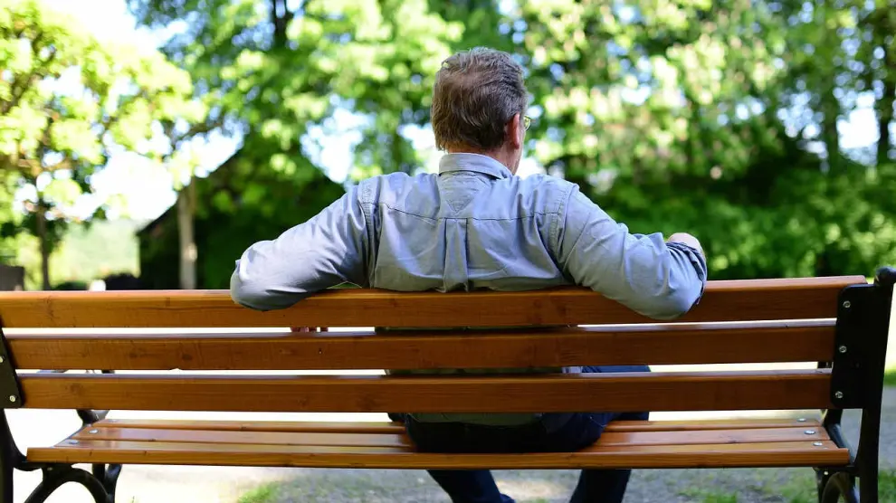 Un hombre jubilado sentado en un banco.