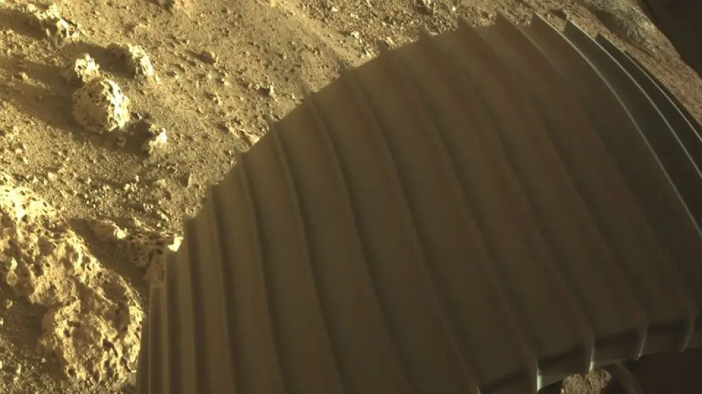 Una de las ruedas del Perseverance, mientras es bajado por una grúa hasta la superficie de Marte.