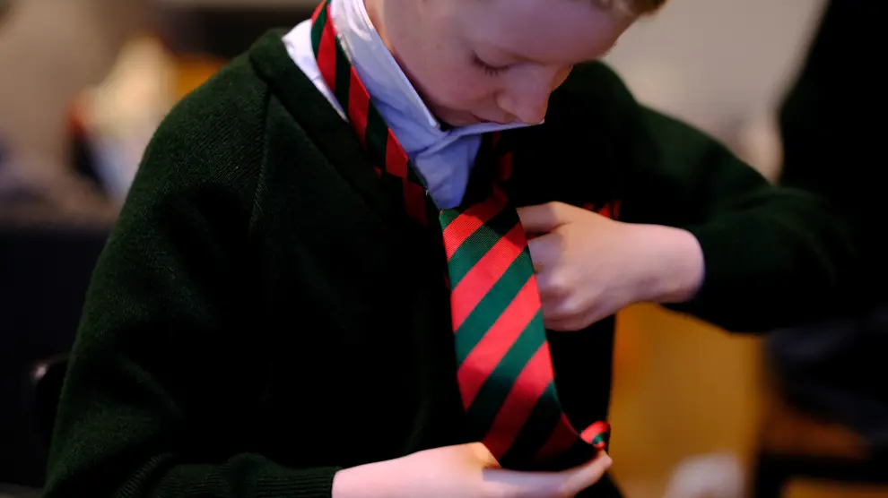 A school boy fastens his tie as he prepares to return to school amid the outbreak of the coronavirus disease (COVID-19) in Manchester, Britain, March 8, 2021. REUTERS/Phil Noble[[[REUTERS VOCENTO]]] HEALTH-CORONAVIRUS/BRITAIN-SCHOOLS