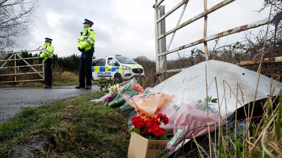 Dos policías vigilan la zona donde aparecieron los restos de la joven, donde se han depositado varios ramos de flores