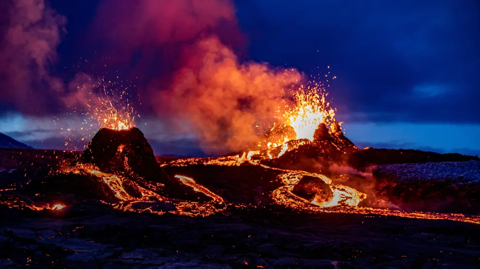 People watch as lava oozes from a new fissure near Fagradalsfjall, Reykjanes Peninsula, Iceland April 5, 2021 in this picture obtained from social media. Ao Thor/via REUTERS ATTENTION EDITORS - THIS IMAGE HAS BEEN SUPPLIED BY A THIRD PARTY. MANDATORY CREDIT. NO RESALES. NO ARCHIVES.[[[REUTERS VOCENTO]]] ICELAND -VOLCANO/