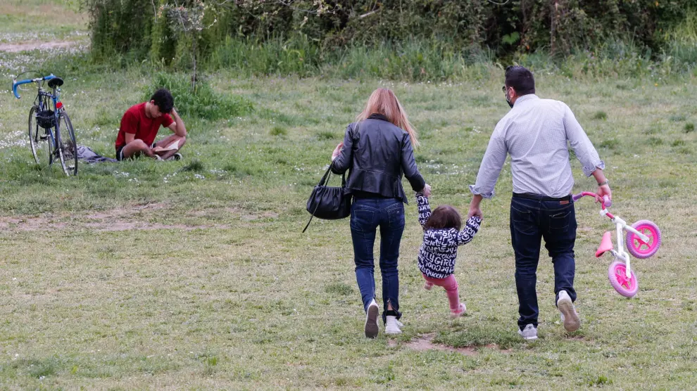 Unos padres pasean con su hija por un parque de Roma.