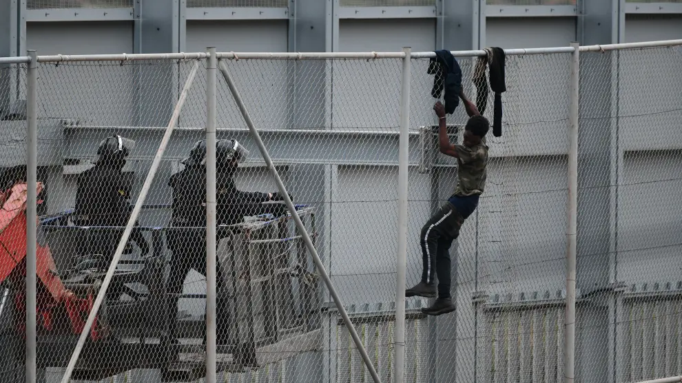 Un inmigrante intenta saltar la valla fronteriza de Ceuta, este martes.