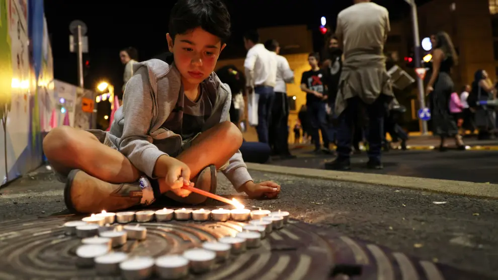 A boy lights candles during a vigil for the people killed and injured in a stampede at an ultra-Orthodox Jewish festival on the slopes of Israel's Mount Meron, in Jerusalem