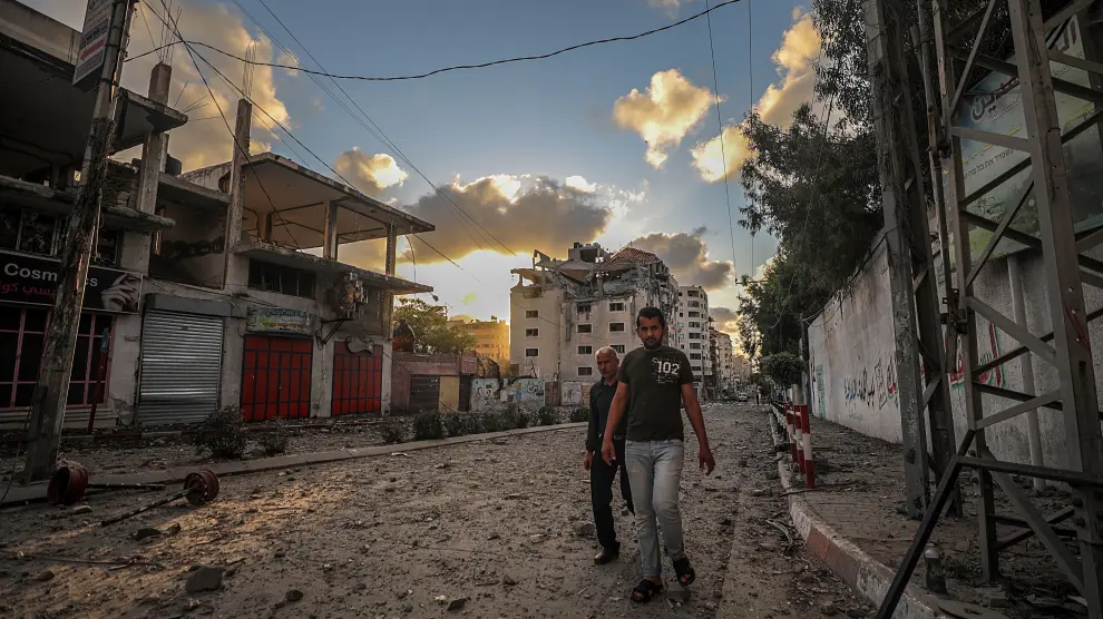 Dos palestinos caminan por una calle de Gaza, destrozada por los bombardeos israelíes