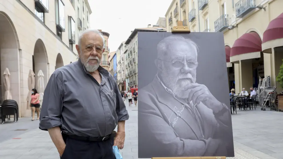 Gonzalo Suárez posa junto a su retrato en los Porches de Galicia.