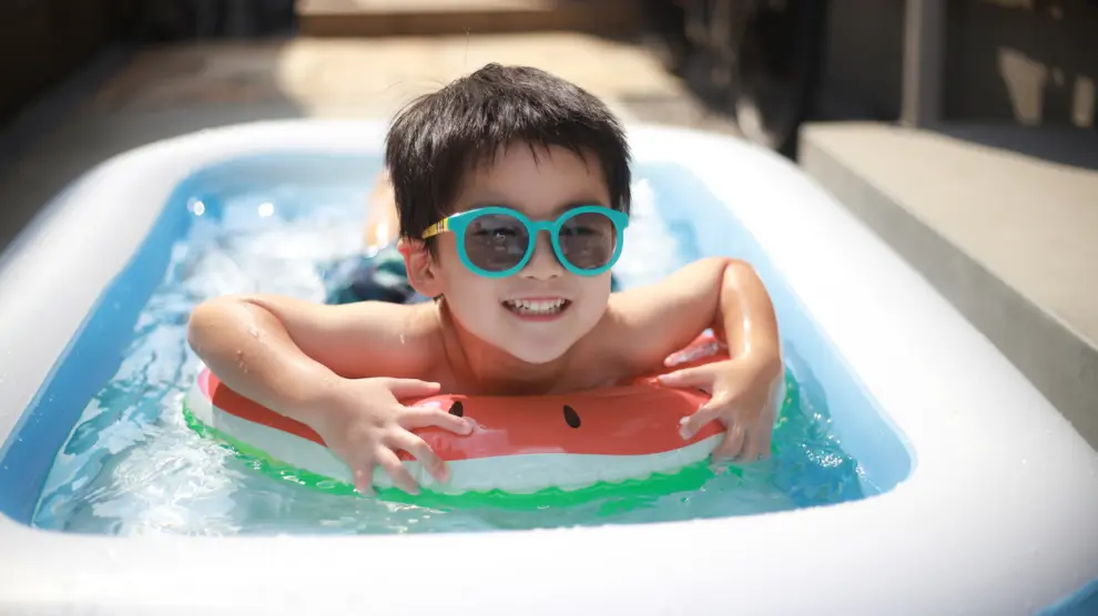 Niño disfrutando de su piscina hinchable en la terraza