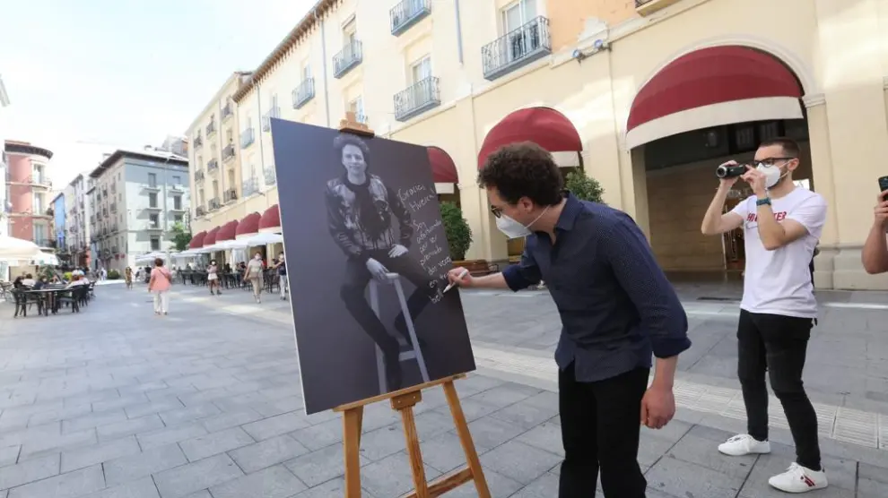 Michel Franco firma el póster con su retrato en los Porches de Galicia.