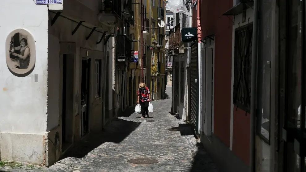 A woman wearing a protective mask carries bags in Alfama neighbourhood, amid the coronavirus disease (COVID-19) pandemic, in Lisbon