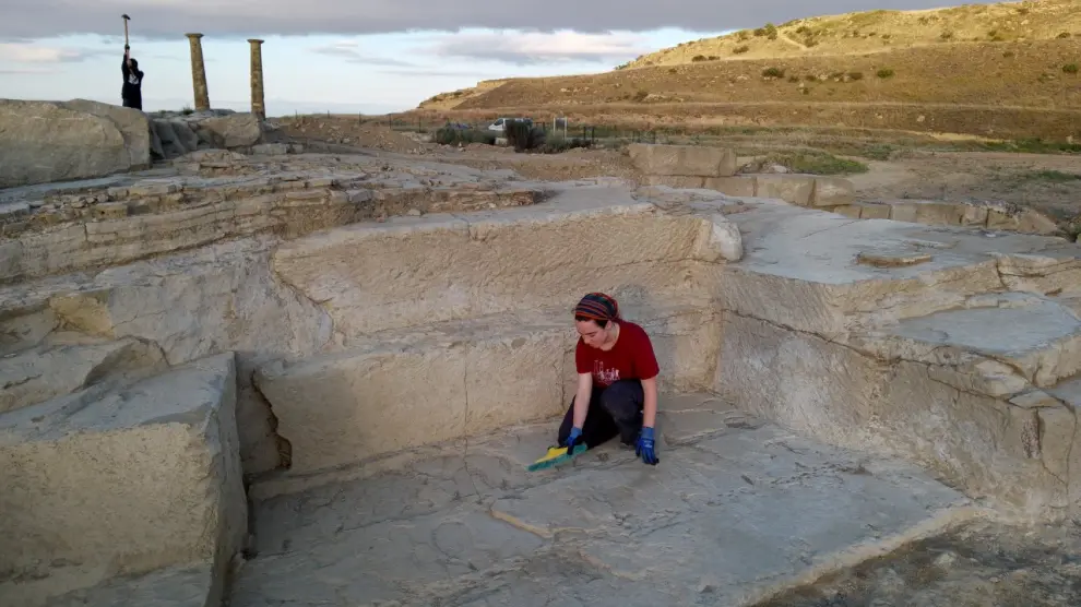 Una estudiante que participa en la excavación limpia los restos de la cantera de piedra encontrada en Los Bañales.